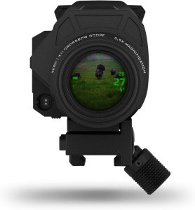 Black tactical riflescope with a digital green HUD showing numbers and a grassy field in the lens