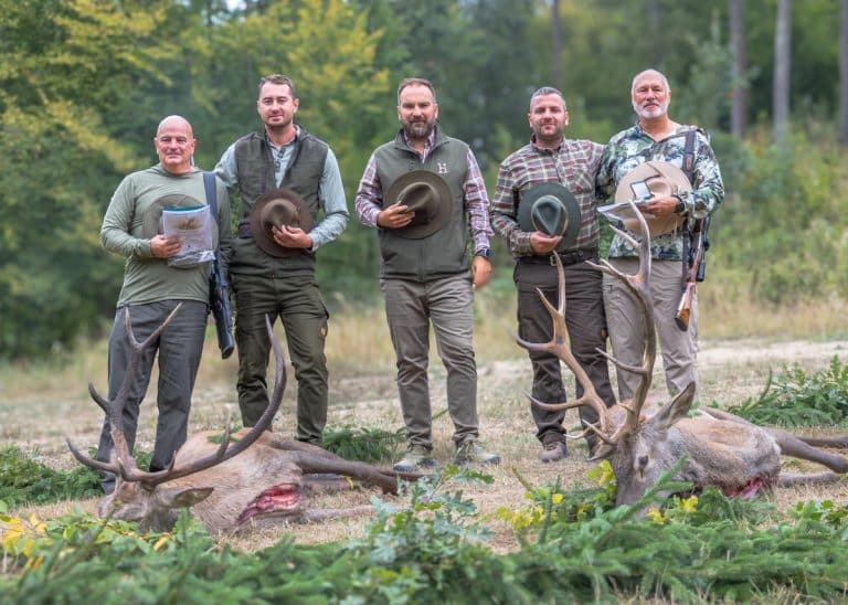 European red stag hunting adventure with Heming Hunting, featuring hunters and guides posing with two trophy red stags after a successful hunt in Europe.